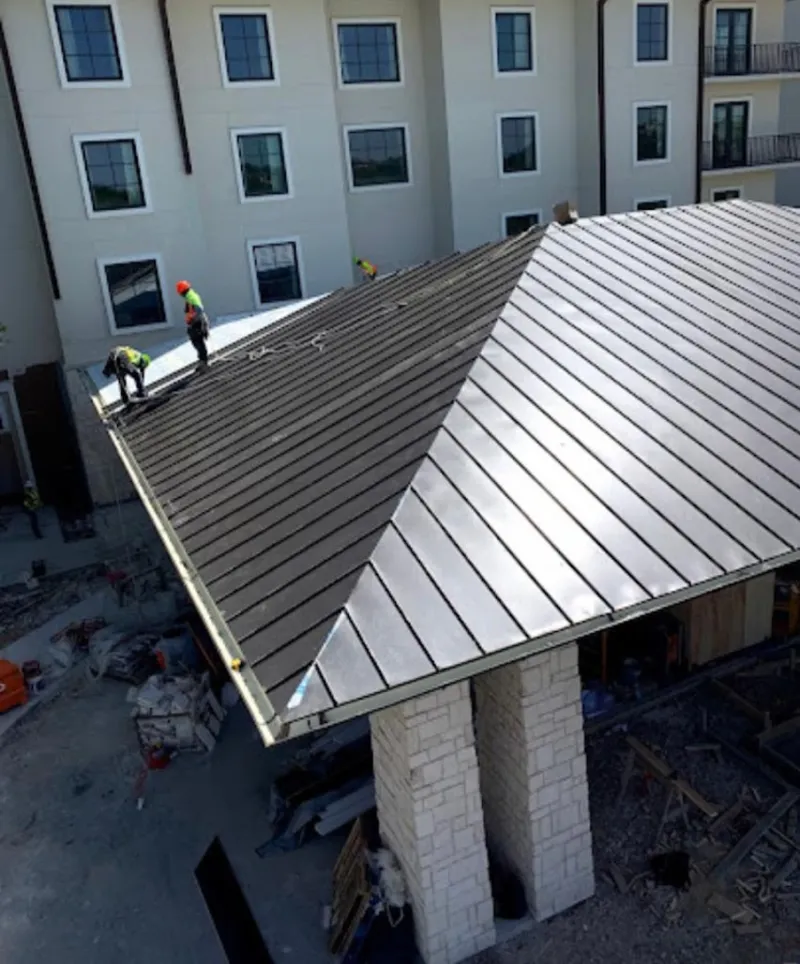 Crew installing standing seam metal roof panels on a commercial project in Crowley
